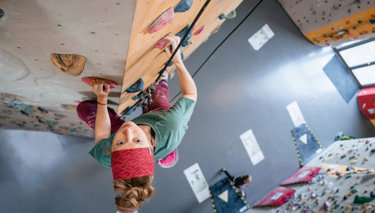 Eine Frau klettert in einer Kletterhalle, ihr Partner sichert sie. | © DAV/Marisa Koch