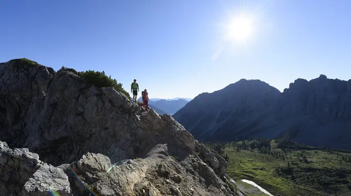 Zwei Wanderer auf einem Felsgrat. Im Hintergrund grüne Bergwiesen | © DAV / Wolfgang Ehn